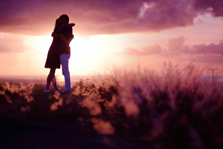 Young couple enjoying the sunset in the meadowの写真素材