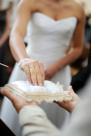 Bride taking a ring from a pillow during wedding ceremonyの写真素材