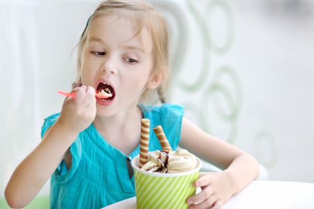 Adorable little girl eating ice cream at summerの写真素材