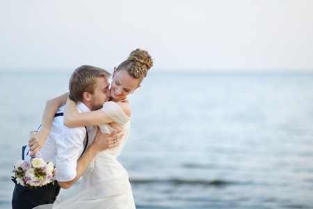 Beach wedding: bride and groom hugging by the seaの写真素材