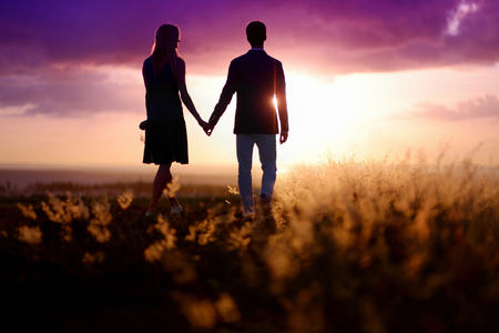 Young couple enjoying the sunset in the meadowの写真素材