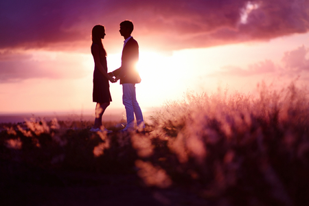 Young couple enjoying the sunset in the meadowの写真素材