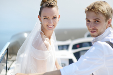 Happy bride and groom hugging on a yachtの写真素材
