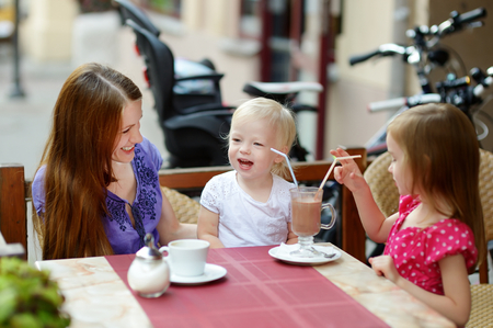 Mother and her daughters relaxing in outdoor restaurantの写真素材