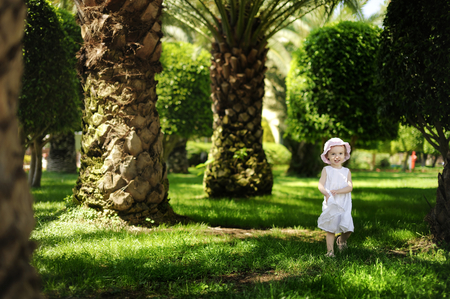 Adorable toddler girl in white dress on tropical resortの写真素材