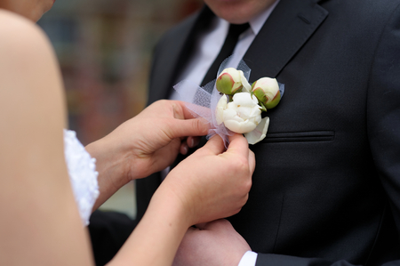 Bride adjusting beautiful groom's boutonniere