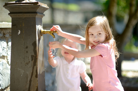 Two sisters having fun with drinking water fountain in Italyの写真素材