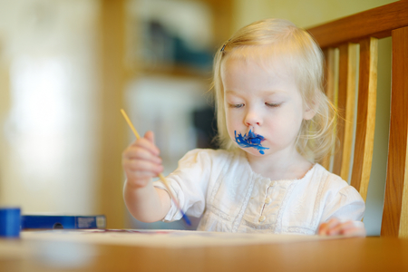 Funny grimy toddler girl painting in daycareの写真素材