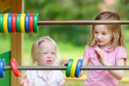 Two little sisters learning to count at a playgroundの写真素材