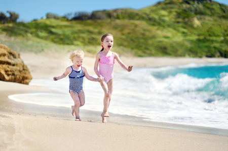 Two little sisters having fun on a sandy beachの写真素材