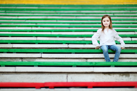 Cute little girl sitting on a stadium seatの写真素材