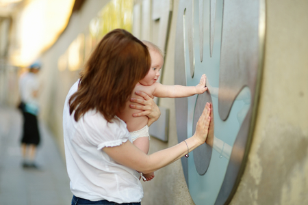 Happy young mother with her baby son on beautiful sunny summer parkの写真素材