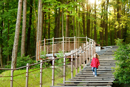 Adorable girl walking down stairs in summer park on beautiful sunny dayの写真素材