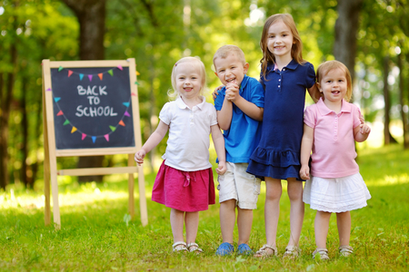 Four adorable little kids feeling very excited about going back to schoolの写真素材