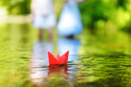 Red paper boat floating on a riverの写真素材