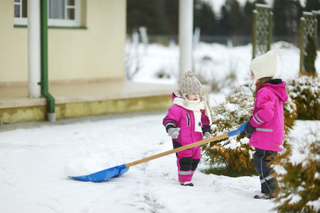 Two little sisters having fun on white and snowy winter dayの写真素材