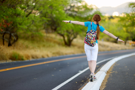 Young tourist with a backpack hitchhiking along a roadの写真素材
