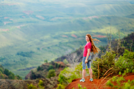 Young woman enjoying stunning view into Waimea Canyon, Kauai, Hawaiiの写真素材