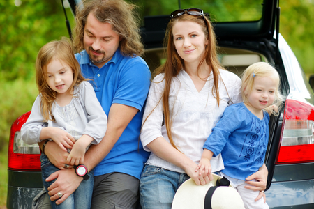 Happy family of four sitting in a car just before leaving for a car vacationの写真素材