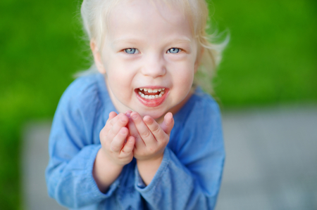 Cute little girl having fun running and laughing on a sunny summer dayの写真素材