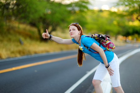 Young tourist with a backpack hitchhiking along a roadの写真素材