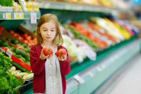 Little girl choosing tomatoes in a food storeの写真素材