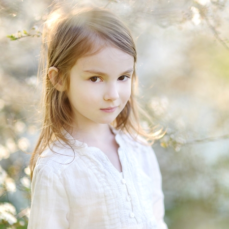 Adorable little girl in blooming cherry garden on beautiful spring dayの写真素材
