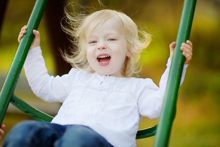 Adorable girl having fun on a swing on summer dayの写真素材