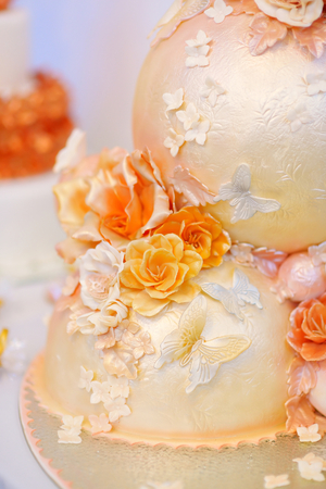 Fancy delicious white and yellow wedding cake decorated with flowers and butterfliesの写真素材