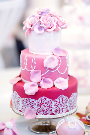White wedding cake decorated with pink sugar flowersの写真素材