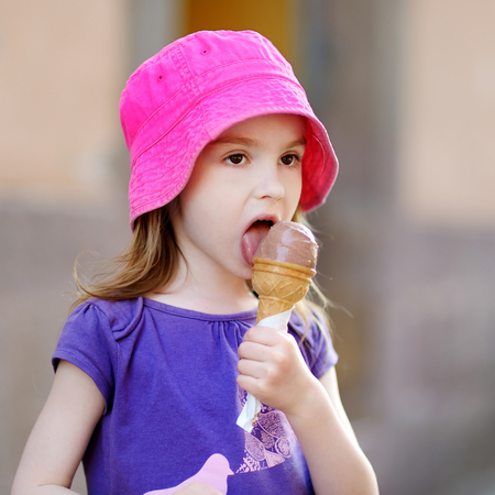 Adorable little girl eating ice-cream outdoors at summerの写真素材