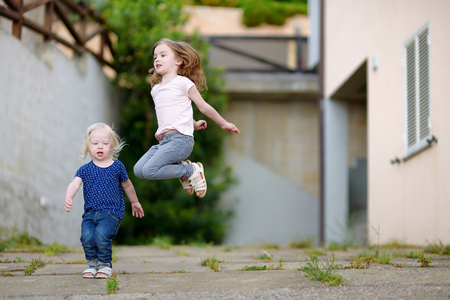 Portrait of two cute funny little sisters outdoorsの写真素材