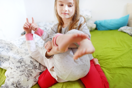 Two little sisters fooling around, playing and having fun in bed on sunny sunday morningの写真素材