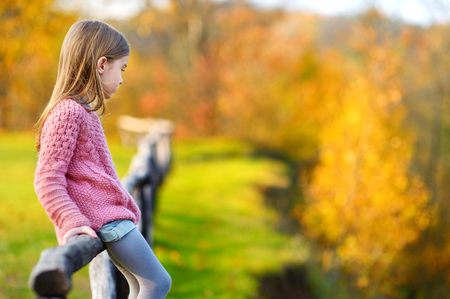 Portrait of a cute little girl on beautiful golden autumn dayの写真素材