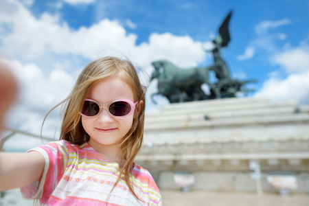 Adorable little girl wearing sunglasses taking a photo of herself in Rome, Italyの写真素材