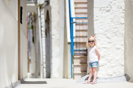 Adorable little girl on warm and sunny summer day in typical italian townの写真素材