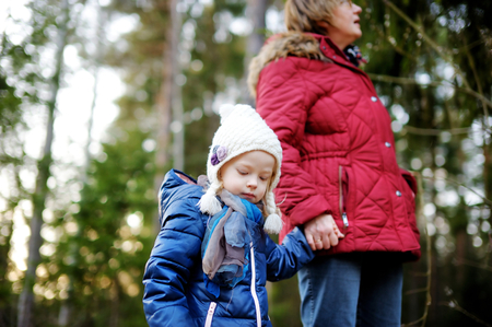 Little girl and her grandmother taking a walk on autumn forest