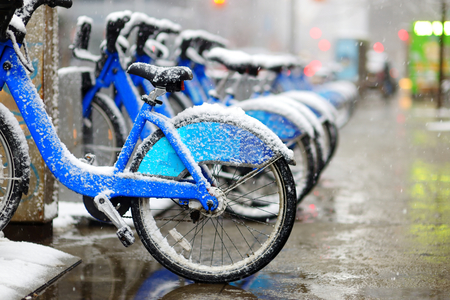 Row of rental city bikes at docking station covered with snow in New York at winterの写真素材