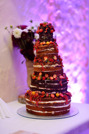 Delicious chocolate wedding cake decorated with fruits and berriesの写真素材