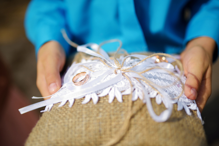 Child holding a pillow with the wedding rings on it before catholic wedding ceremony in churchの写真素材
