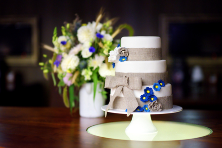 Three stories wedding cake decorated with blue flowers and a ribbon