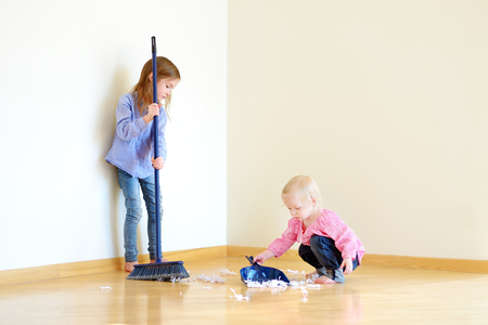 Two cute girls helping her mom to clean up at homeの写真素材