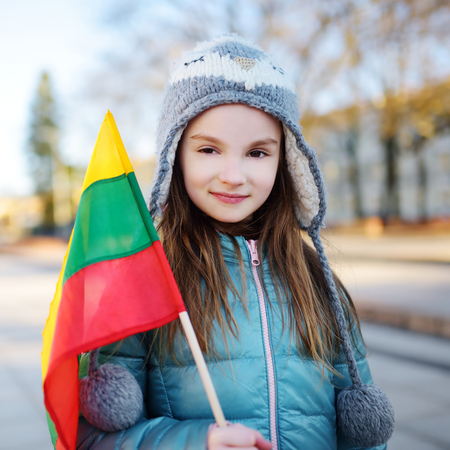 Cute little girl celebrating Lithuanian Independence Day holding tricolor Lithuanian flag in Vilniusの写真素材