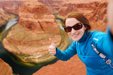 Young tourist taking a photo of herself by famous Horseshoe Bend, Arizona, USAの写真素材