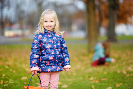Little girl gathering acorns for crafting and playing on beautiful autumn day outdoorsの写真素材