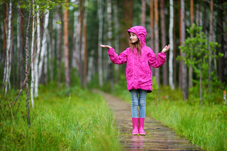 Adorable little girl playing happily in the rain on warm summer dayの写真素材