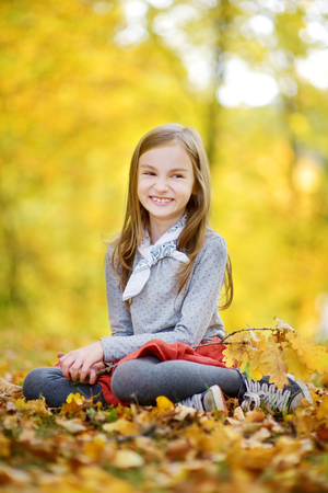 Cute little girl having fun on beautiful autumn day outdoorsの写真素材