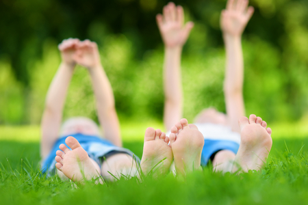 Two childrens feet on grass outdoors in summer parkの写真素材