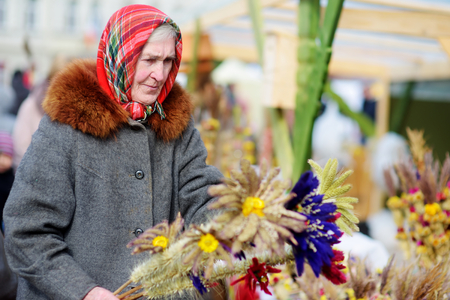 VILNIUS, LITHUANIA - MARCH 4, 2016: Senior woman selling traditional handmade Lithuanian Easter palm known as verbos. Vilnius annual traditional crafts fair is held every March on Old Town streets.のeditorial素材