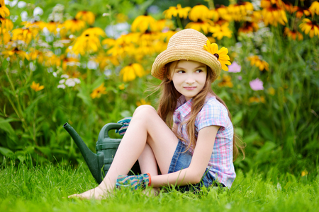 Cute little girl watering flowers in the garden at summer dayの写真素材